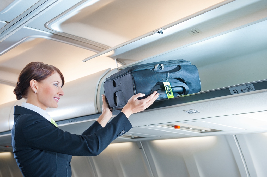 стюардесса кладет багаж на полку в самолете, каких размеров должна быть ручная кладь, куда положить чемодан в самолете