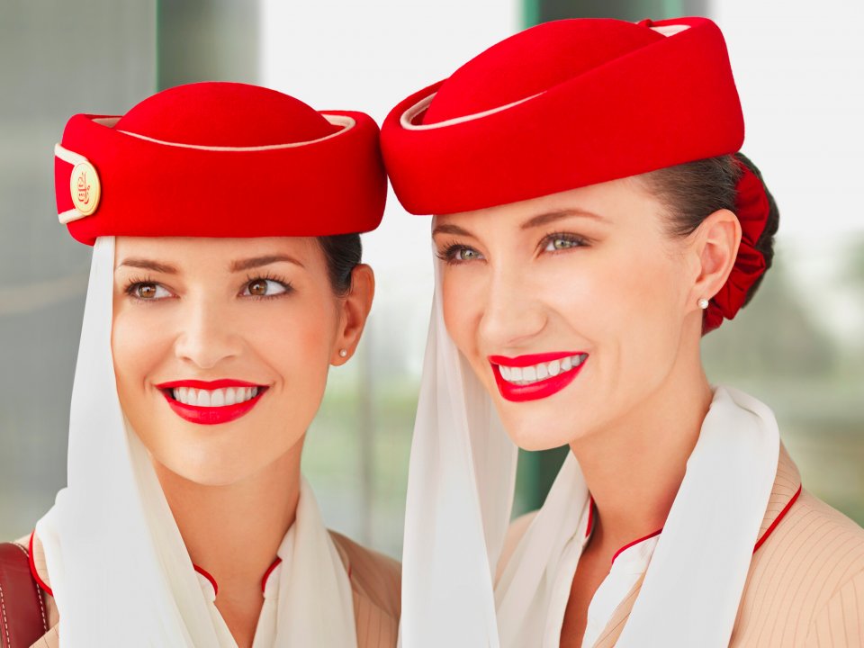 очень красивые стюардессы Emirates Airlines в шапке с вуалью и с красной помадой на губах, девушки с белоснежной улыюкой улыбаются