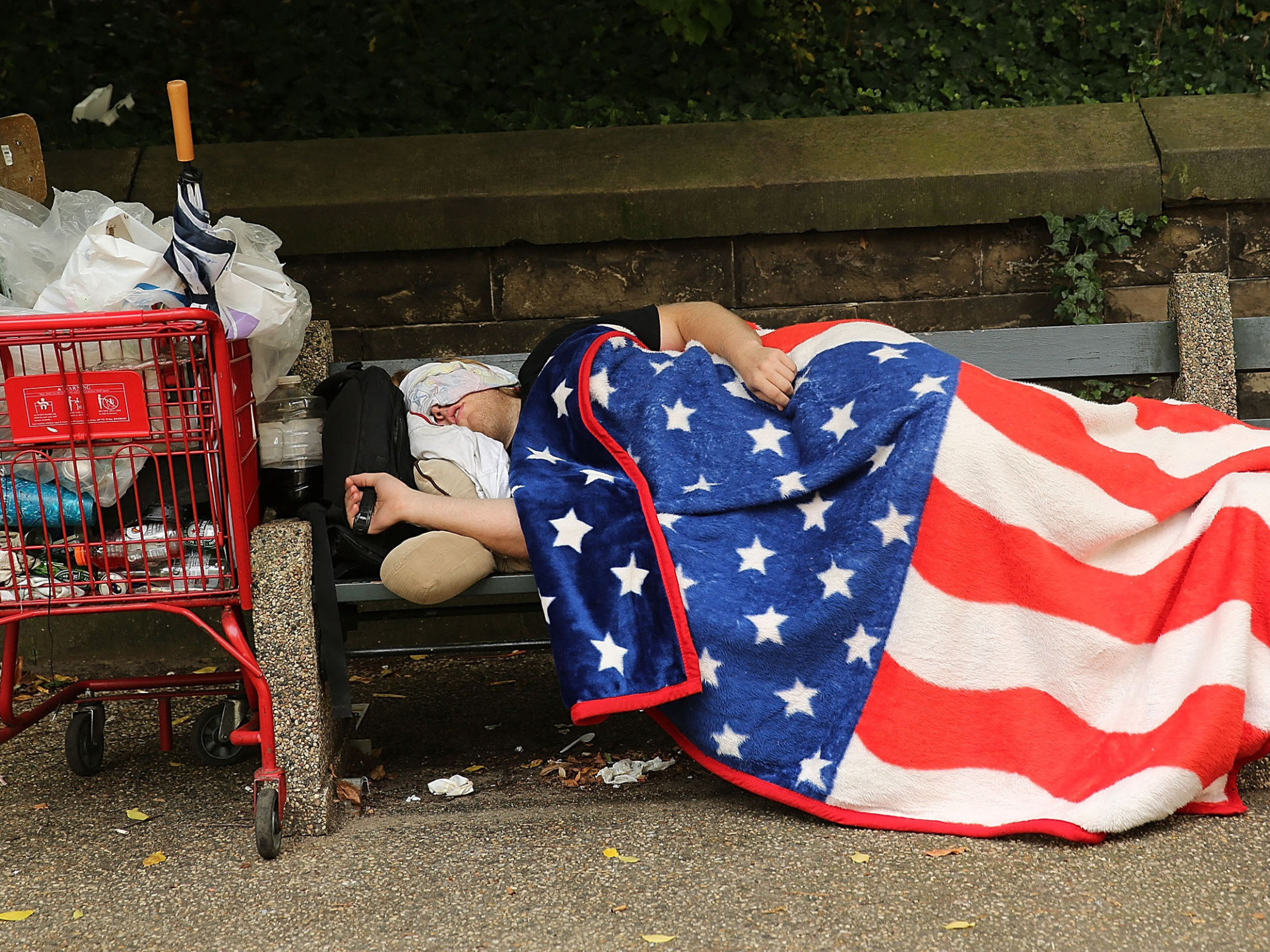 приезжий студент иммигрант спит на улице в США - высокие цены на жилье в Америке - парень с американским флагом
