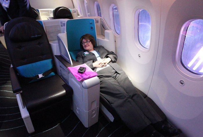 женщина спит на раскладном кресле бизнес класса в самолете
