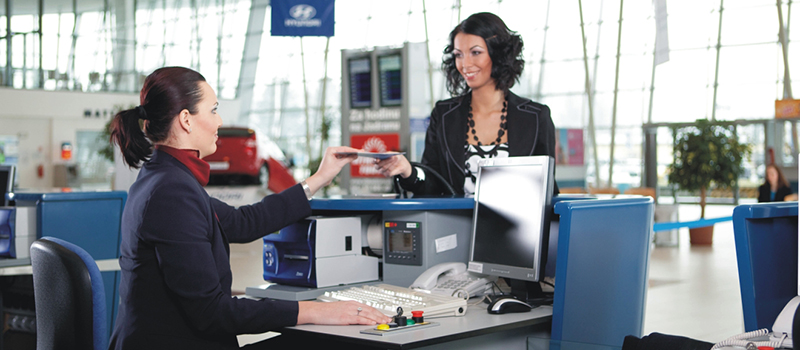 красивая приветливая улыбчивая девушка на стройке регистрации в аэропорту чекинится - cheсk-in авиакомпании и сдача багажа